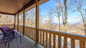 A wooden deck with a railing, two wicker chairs, and a view of trees and mountains. - Walk to Beech Mtn Resort, Sleeps 12, Game Room (Beech Mountain)