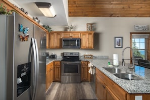 A modern kitchen with wooden cabinets, stainless steel appliances, and a granite countertop.