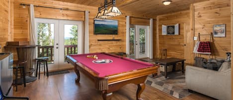 Un interior de madera con mesa de billar, televisor y mesa de futbolín.