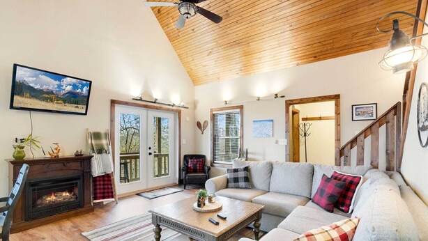 A cozy living room with a fireplace, a large sofa, a coffee table, and a television mounted on the wall. - Walk to Beech Mtn Resort, Sleeps 12, Game Room (Beech Mountain)