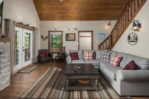 A living room with a grey sofa, a wooden coffee table, and a staircase with wooden railings.