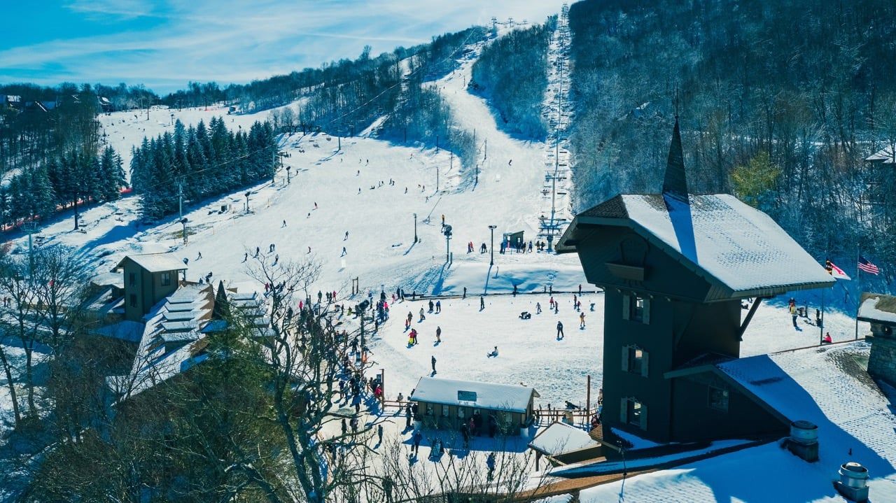 Ein Skigebiet mit Sessellift, Skipisten und einer Berghütte.