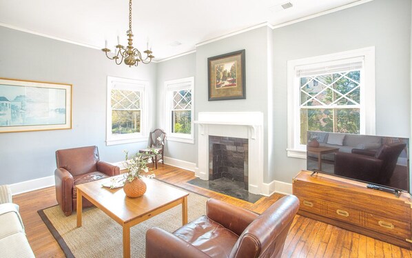 A living room with a fireplace, leather furniture, and a television.