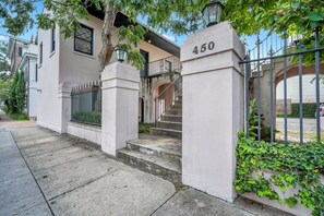 A building with a white facade, a number '450' sign, and a gated entrance with a staircase leading to a balcony.