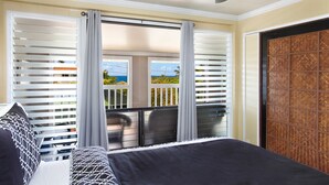 Ein Schlafzimmer mit Bett, einem Balkon mit Blick und einer Holztür.