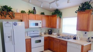 A compact kitchen with wooden cabinets, a white refrigerator, a microwave, an oven, a dishwasher, and a sink. - Tree Top Retreat (Davenport)