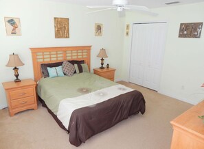 Ein Schlafzimmer mit einem Bett, zwei Nachttischen, einem Deckenventilator und einer Tür.