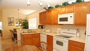 A kitchen with wooden cabinets, a microwave, stove, and a dining table with chairs.