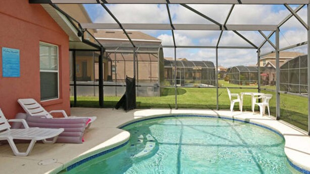 A covered outdoor swimming pool with lounge chairs and a patio area.