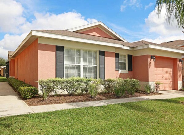 A two-story house with a red exterior, a front porch, and a well-maintained lawn. - Villa Alexa (Davenport)