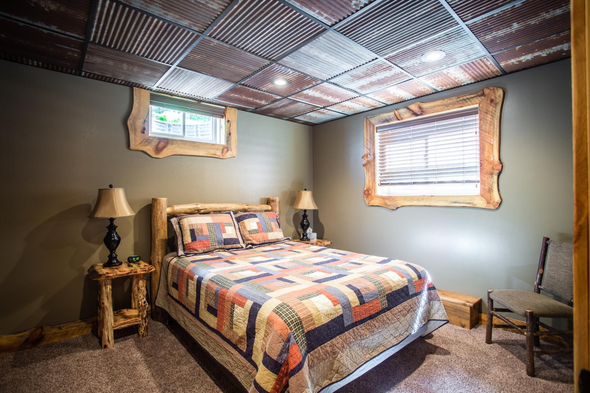 Une chambre à coucher avec un grand lit, deux tables de chevet, une chaise et une fenêtre avec des stores.