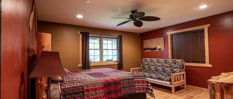 A bedroom with a bed, a chair, a lamp, a ceiling fan, and a window.