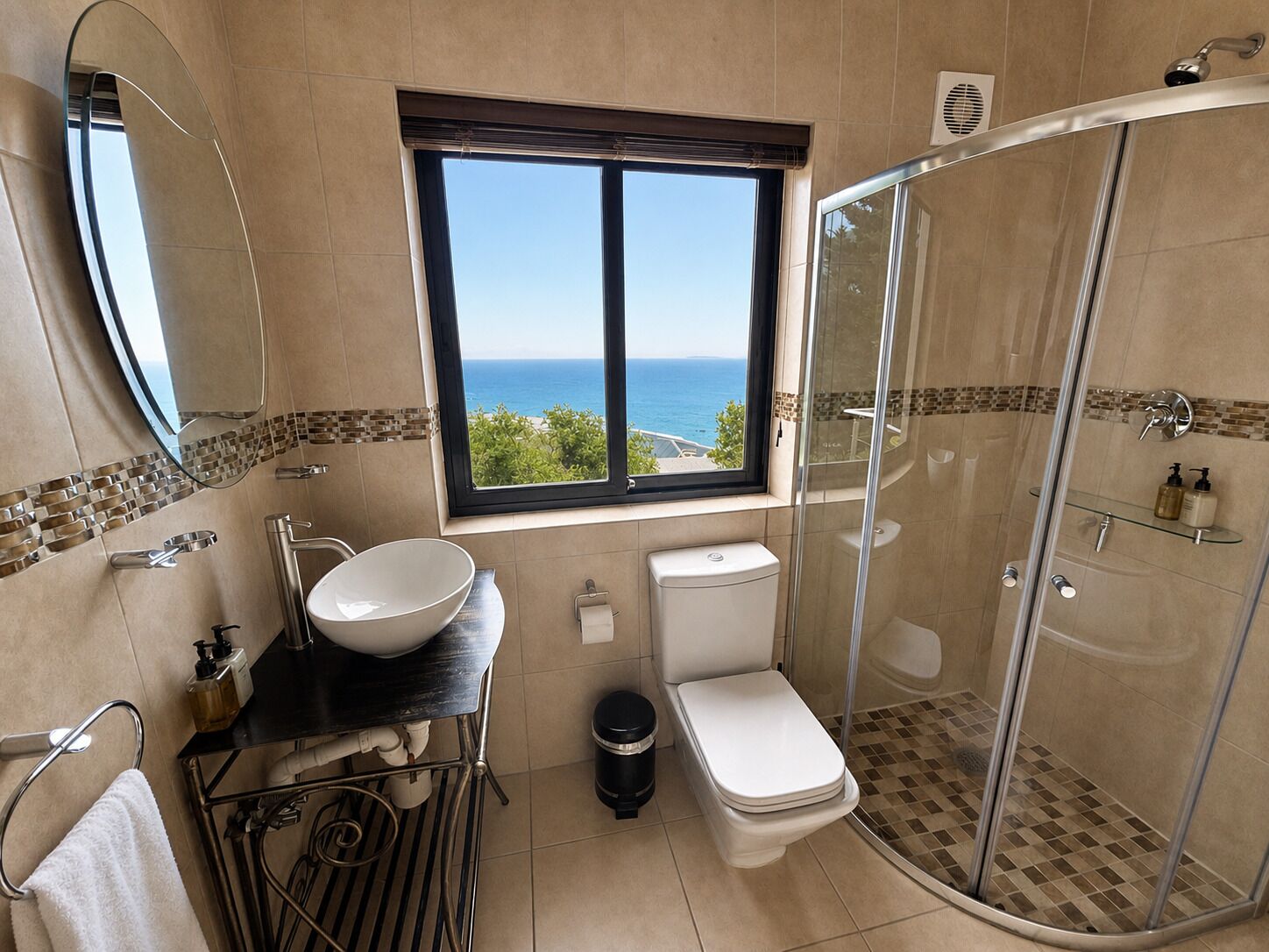 Une salle de bain dotée d’une grande fenêtre, d’une douche à parois de verre et de toilettes blanches.