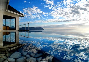 A modern building with a glass balcony overlooking a body of water and a mountainous landscape. - Aqua Terra (Cape Town)