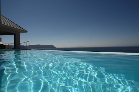 Una piscina al aire libre, sillones reclinables de piscina