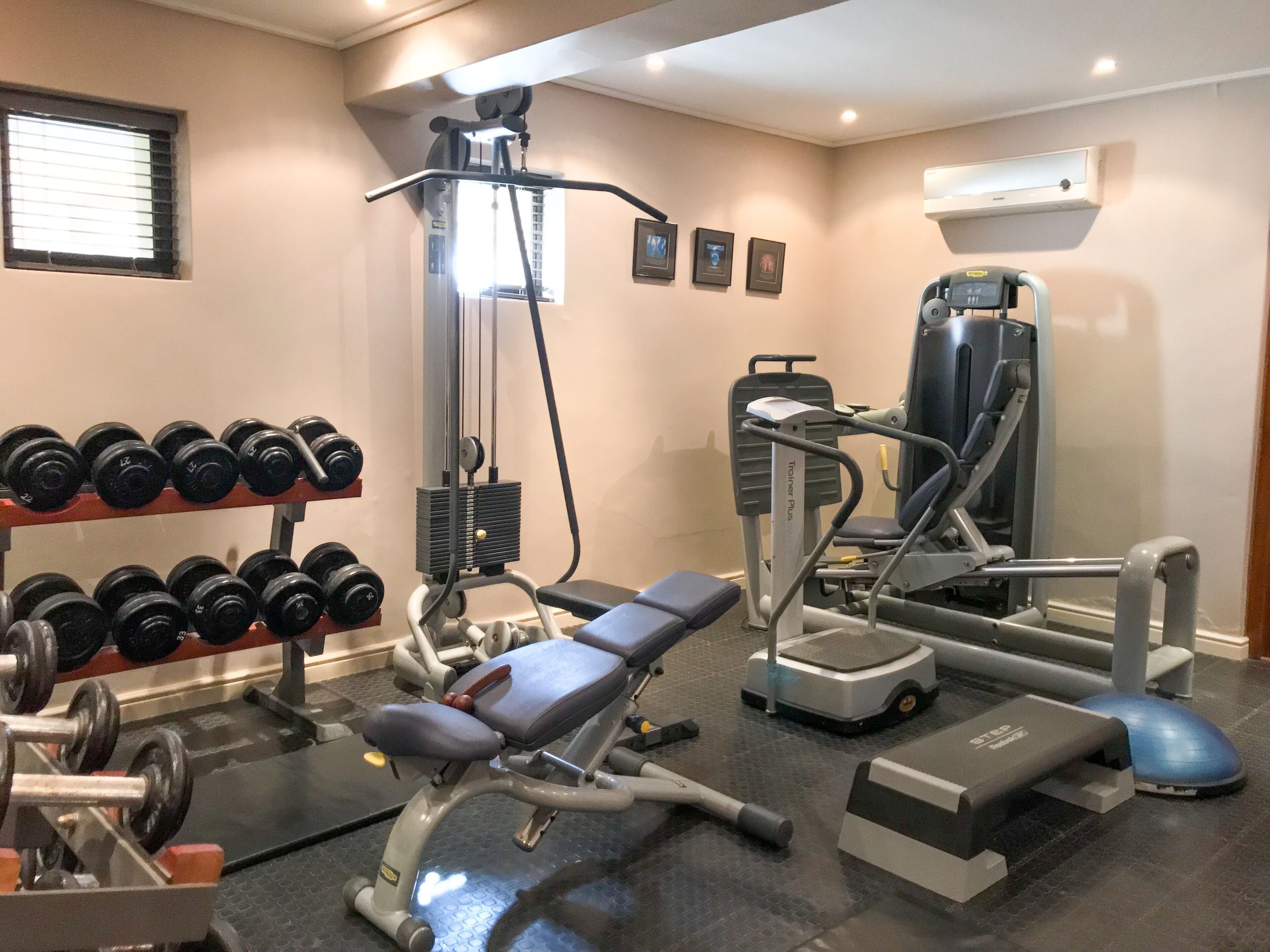 Uma academia com equipamentos de musculação, um banco e uma plataforma elevada.