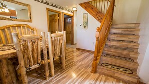 A wooden dining table with chairs, a wooden staircase, and a mirror on the wall. - Romantic Forest Hideaway, Hot Tub, WiFi, near Attractions & Breweries!  (Divide)