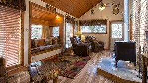 A cozy cabin interior with a wooden ceiling, a fireplace, a seating area with a sofa and chairs, and a rug. - Romantic Forest Hideaway, Hot Tub, WiFi, near Attractions & Breweries!  (Divide)