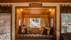 A cozy cabin interior with a wooden bench, a 'Welcome' sign above, and a window with curtains. - Romantic Forest Hideaway, Hot Tub, WiFi, near Attractions & Breweries!  (Divide)
