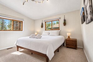 Een slaapkamer met een groot bed, twee nachtkastjes, een raam en een wandlamp.