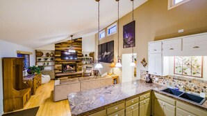 A modern kitchen with a marble countertop, wooden cabinets, and a built-in stove. - Riverfront Hot Tub! Fireplace, Walk to Town (Estes Park)
