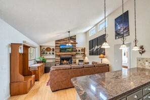 A spacious living area with a fireplace, a large wooden cabinet, and a stone countertop. - Riverfront Hot Tub! Fireplace, Walk to Town (Estes Park)