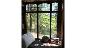 A cozy reading nook with a cushioned bench, a pillow, and a stack of books.