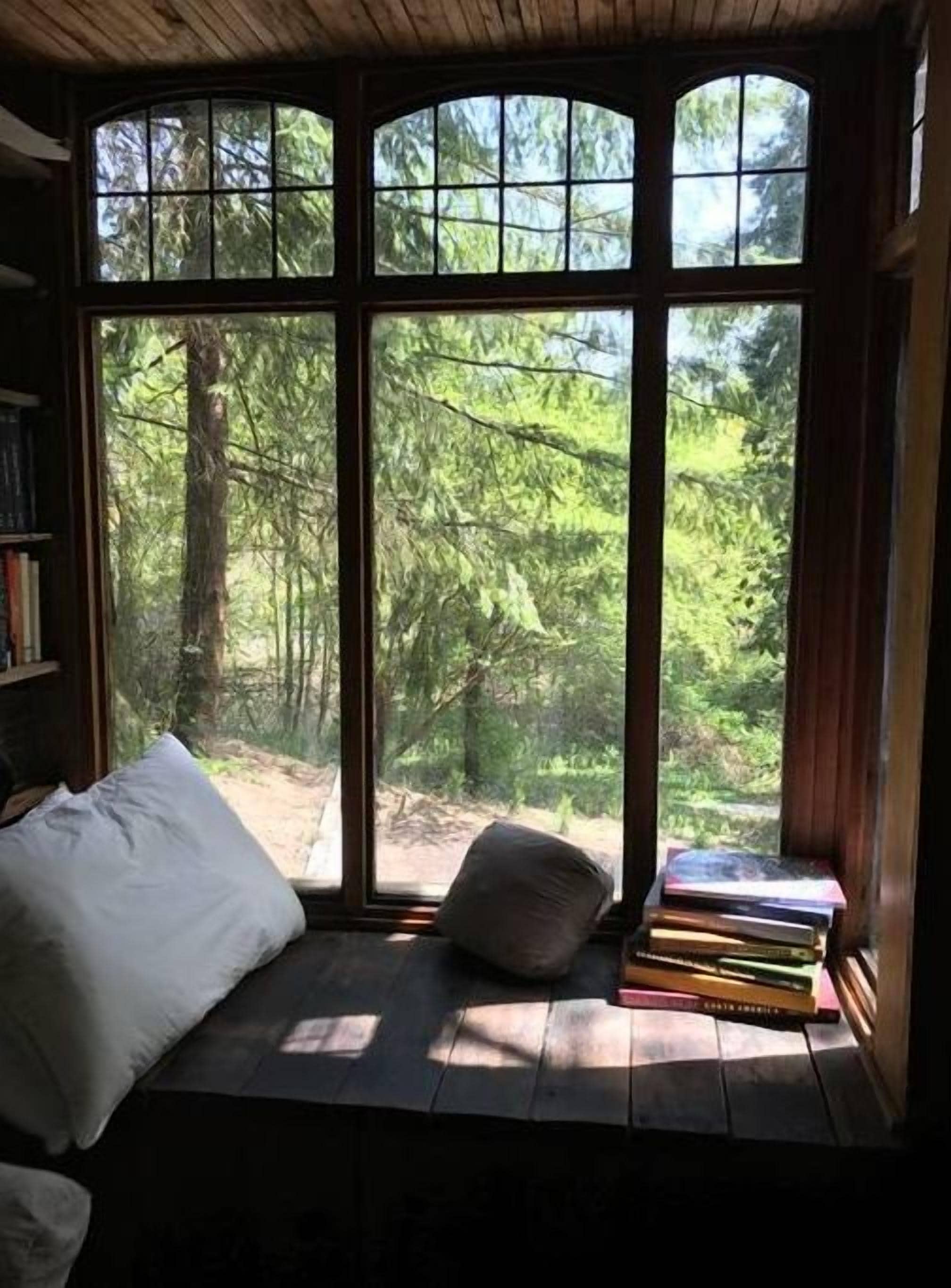 Un coin lecture confortable avec un banc rembourré, un coussin et une pile de livres.