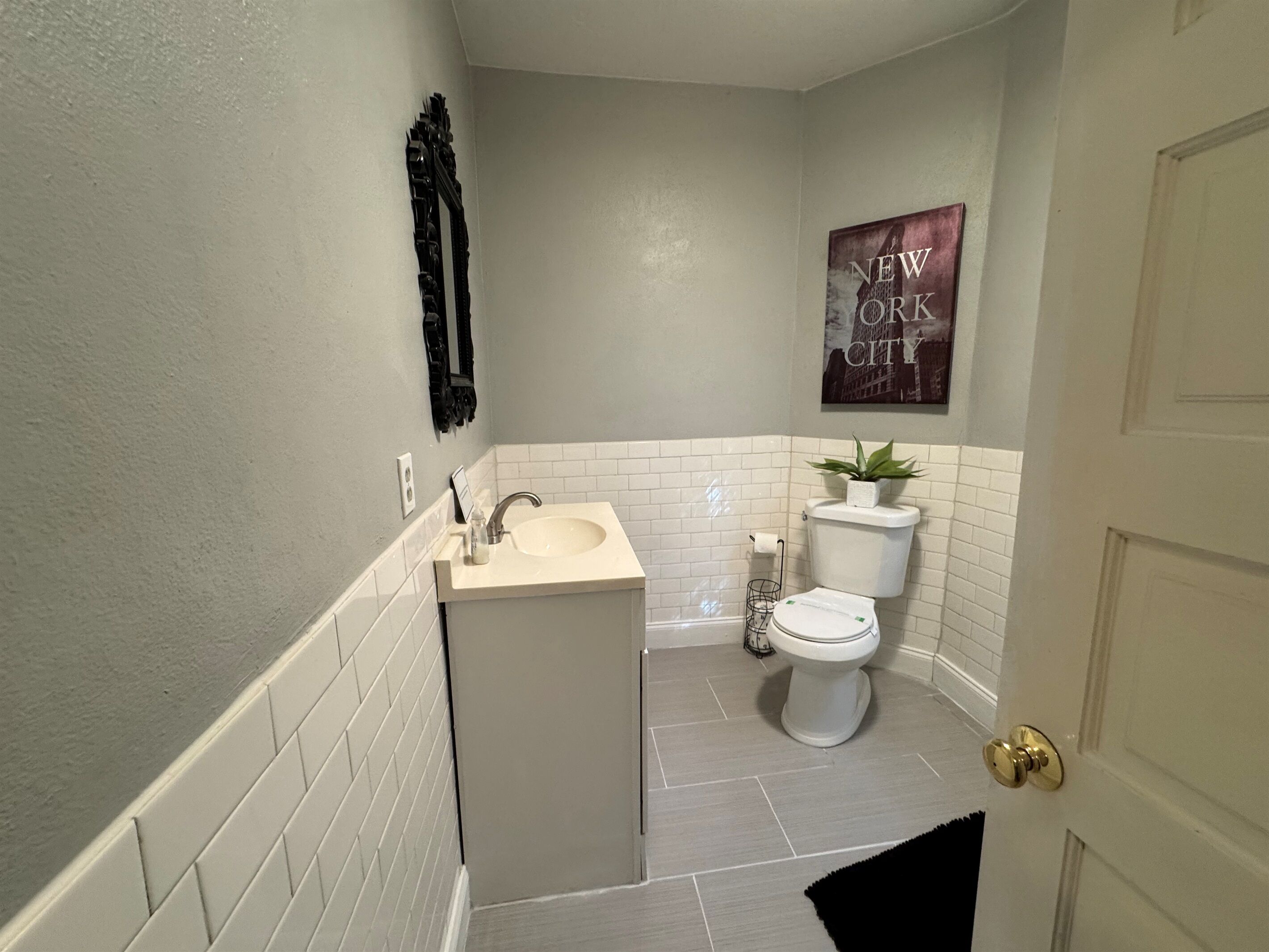 Un baño pequeño con lavamanos, inodoro y una planta en maceta.