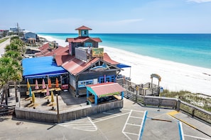 A beachfront building with a red roof, a blue awning, and a sign that reads "Pernambuco Joes." - WALK TO BEACH Condo - Sleeps 6 (Miramar Beach)