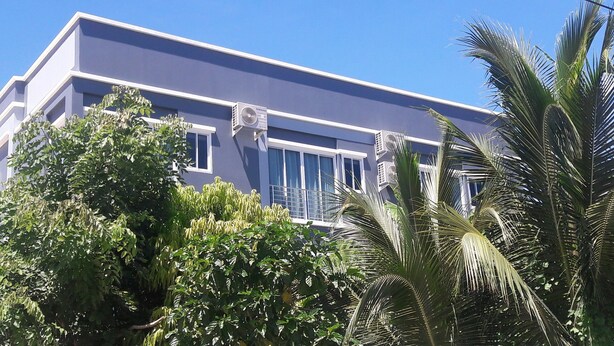 Un edificio moderno con techo plano, ventanas amplias y unidades de aire acondicionado.