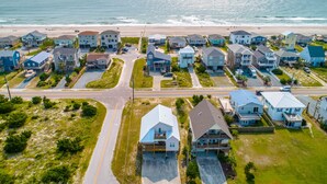 Zona residencial costera con casas que tienen porches y una playa al fondo.