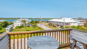 Una terraza de madera con una mesa y sillas, con vista a un puerto deportivo con barcos y casas.