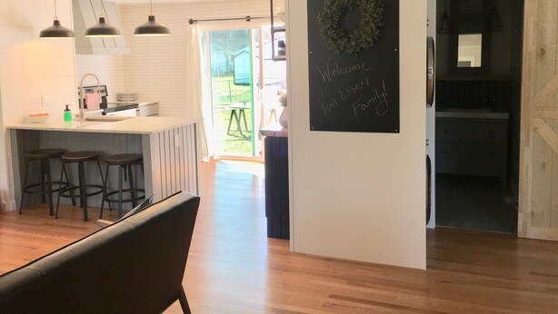 A modern kitchen with pendant lights, a chalkboard sign, and a view to the outdoors.
