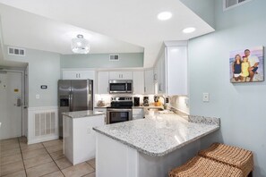 A modern kitchen with white cabinets, stainless steel appliances, and a granite countertop. - NEWLY RENOVATED ~ GROUND FLOOR. Smart TV’s in every room. Steps to Beach & Pool. (Orange Beach)