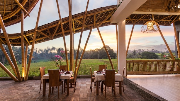 A bamboo structure with a dining area, tables, chairs, and a view of a landscape. - Wadari Retreat Villa Ubud (Ubud)