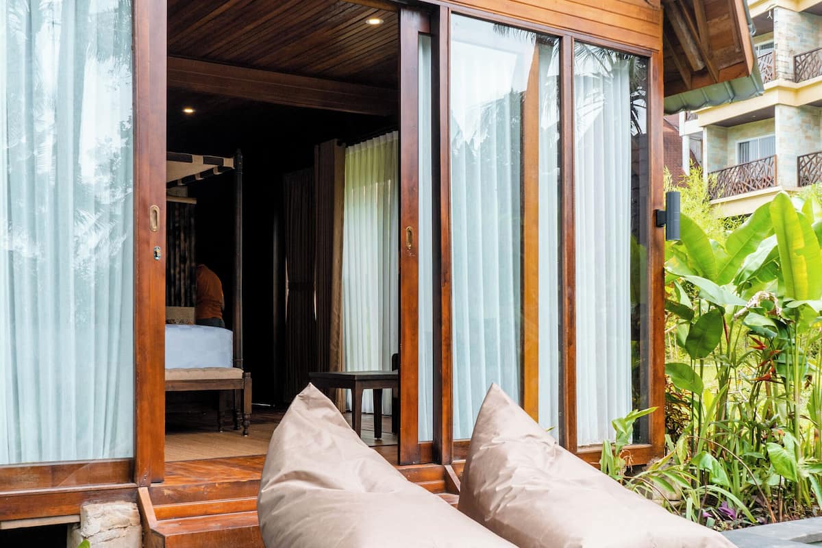 Una villa de madera con piscina, ventanas amplias y vistas al entorno verde.