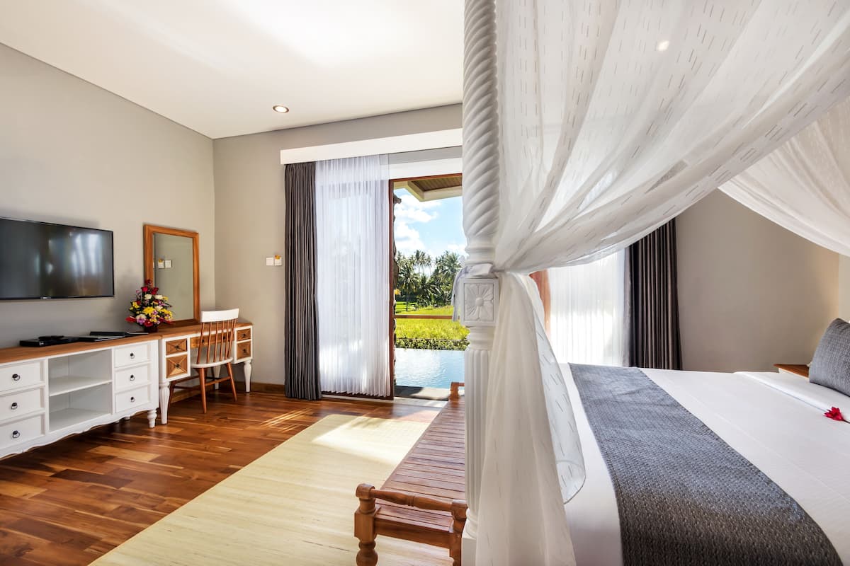 Un dormitorio con cama, televisión, escritorio y vista a una piscina.