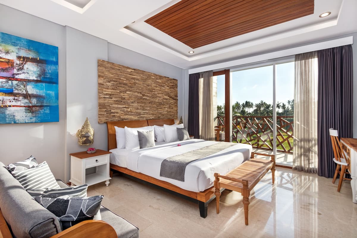 Una habitación de hotel moderna con una cama grande, cabecera de madera, un cuadro, una mesita de noche, un banco y vistas al exterior.