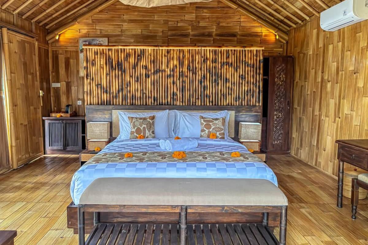 Una habitación de madera con una cama, una mesita pequeña y un banco.
