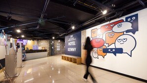 Un hall d’hôtel comprenant un comptoir d’accueil, un écran numérique et un mur décoré de bulles de bande dessinée.