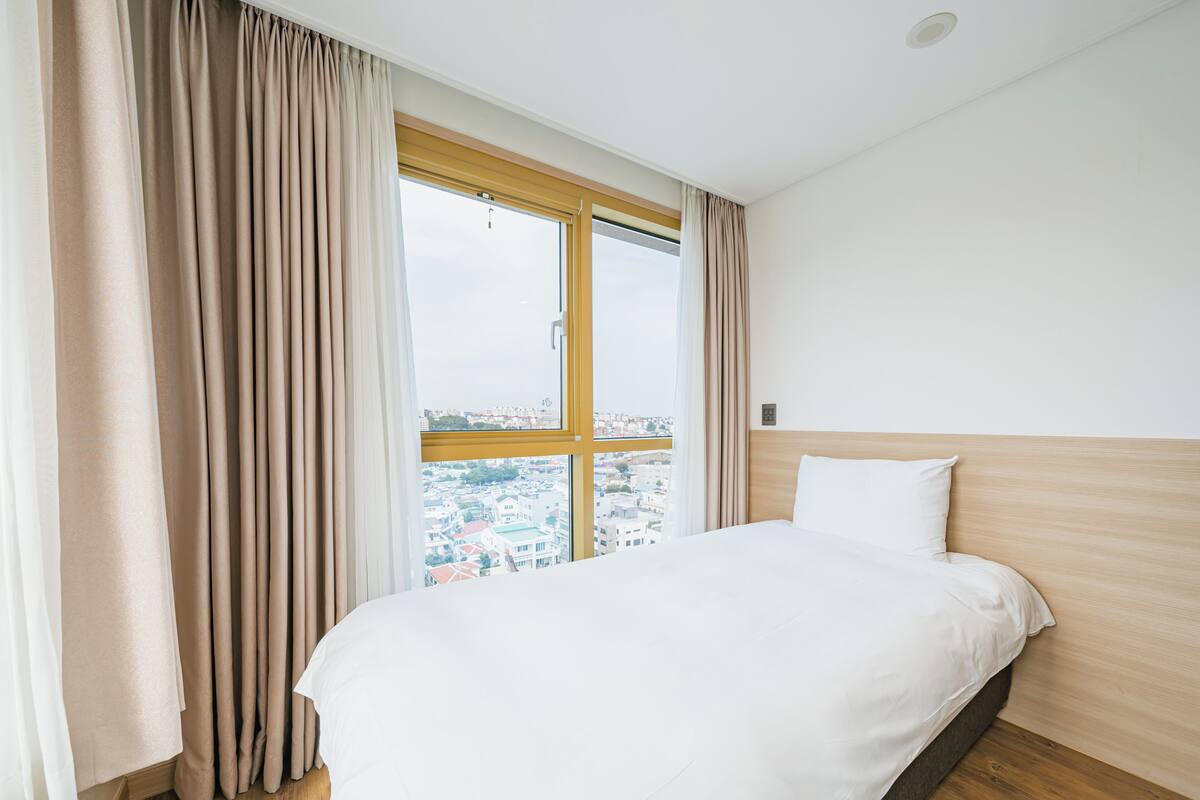 Een hotelkamer met een groot raam, een bed en een houten hoofdbord.
