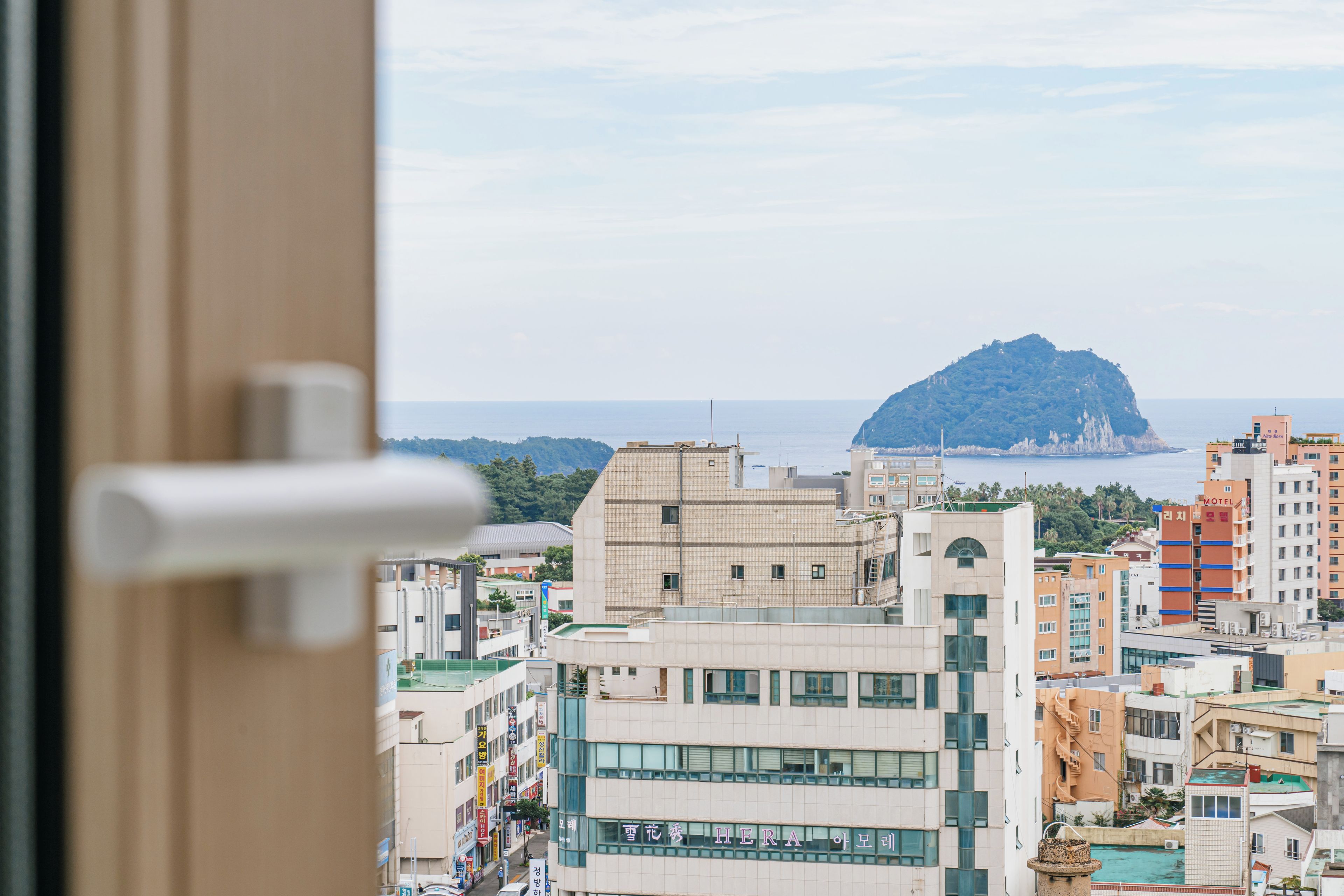 A cityscape with a prominent mountain in the distance, modern buildings, and a clear sky.