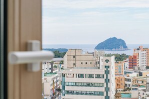 A cityscape with a prominent mountain in the distance, modern buildings, and a clear sky.