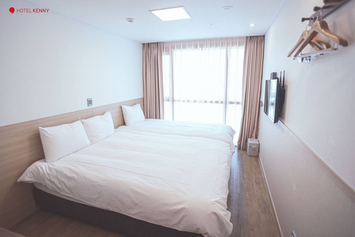Een hotelkamer met een groot bed, een flatscreen televisie aan de wand en een raam met gordijnen.