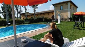 Relax by the pool surrounded by lush greenery and a comfortable lounge chair.