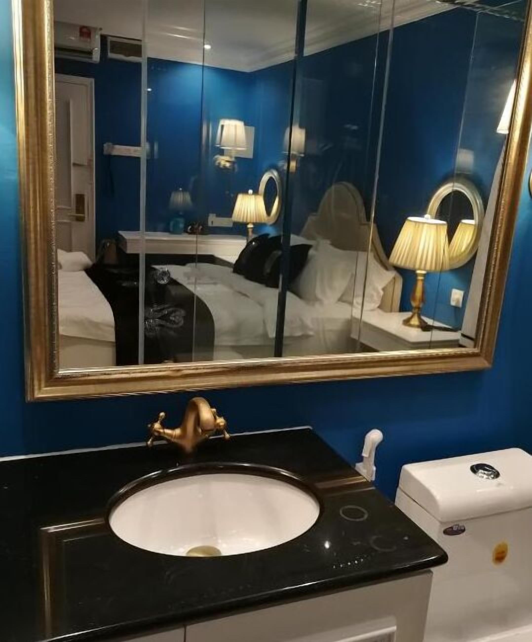 A bathroom with a large mirror, a black sink, and a white toilet.
