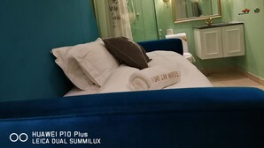 Een hotelkamer met een bed, een badkamer met een spiegel, en een bord dat een rookruimte aangeeft.