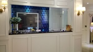 Een moderne badkamer met een grote spiegel, witte lambrisering en een blauwe decoratieve wand.
