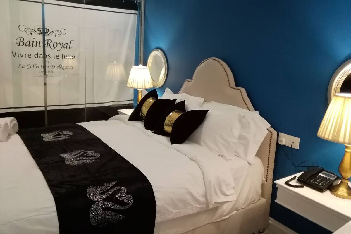 A hotel room with a bed, a nightstand with a lamp, and a wall with a sign.